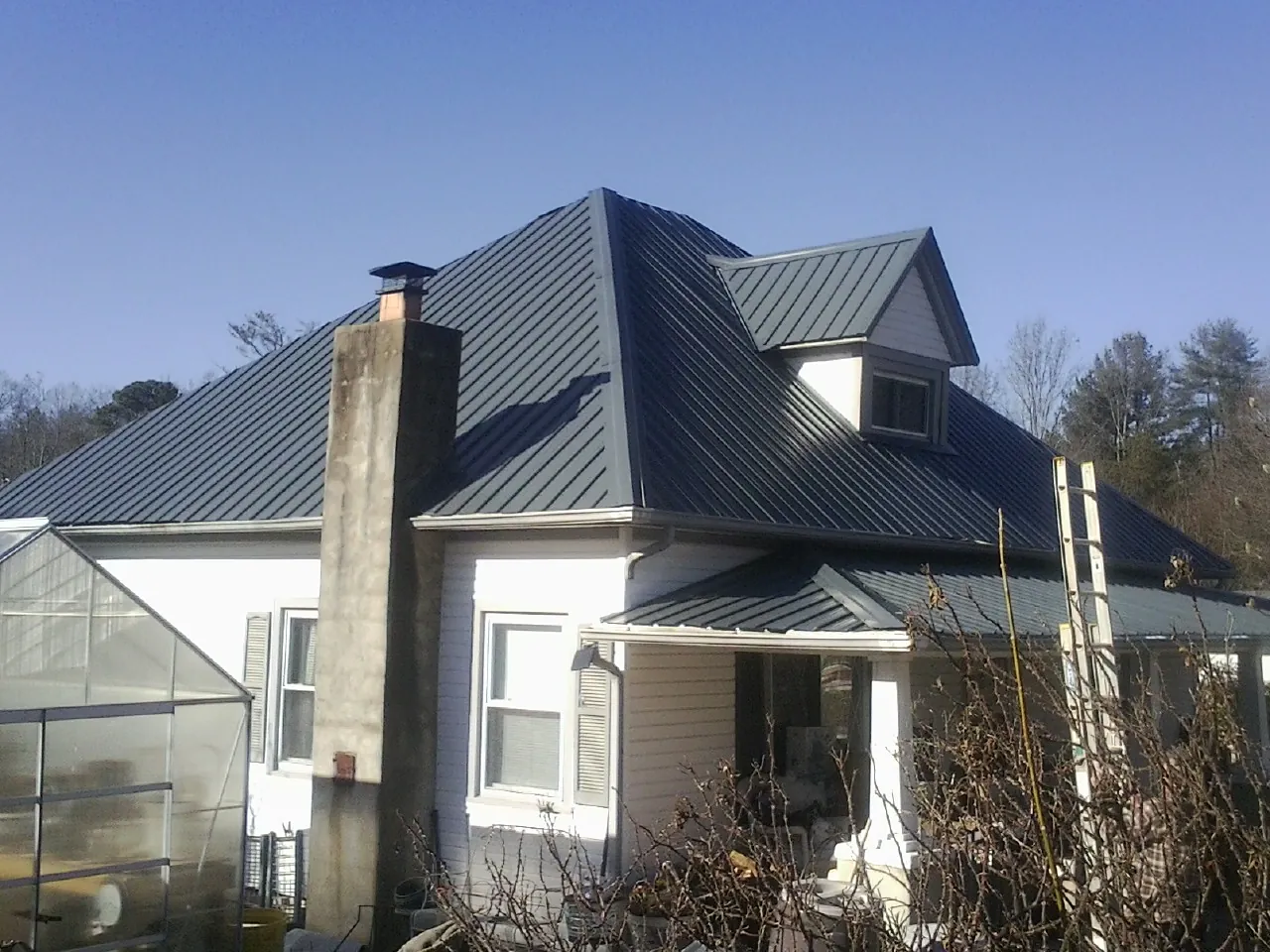Dark blue standing seam metal roof on a white farmhouse with dormer — Slate & Tile Roof Repair by Roofing Brothers in Tabernash
