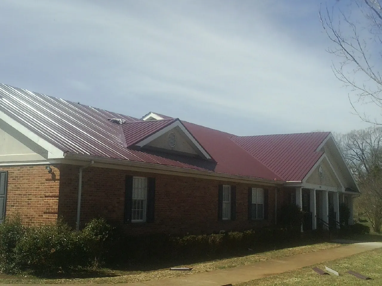 Red metal roof with gabled entries on a long brick building, from a Hail Damage Roof Repair job in Tabernash