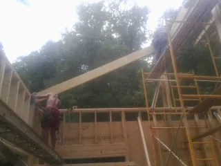 Carpenter raising a rafter beam on a new second story frame in Tabernash