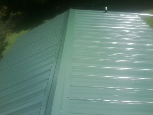New green metal panels meeting at the ridge of a roof — Flat Roof Repair work by our crew in Tabernash