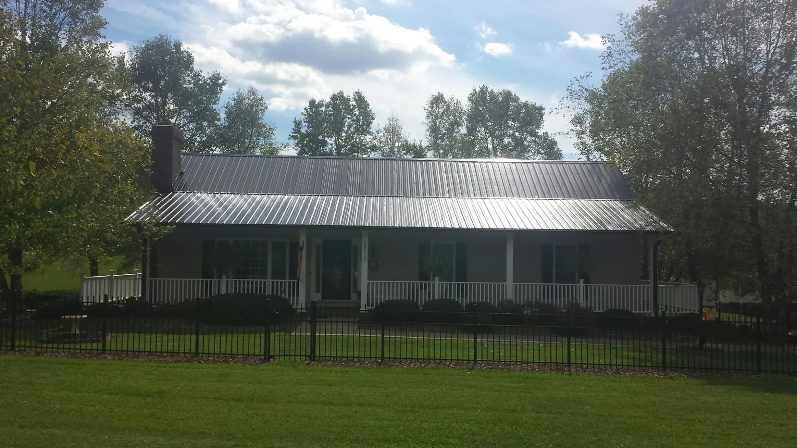 Gray metal roof on a brick ranch with a full width front porch — Gutter Guard Installation work by our crew in Tabernash