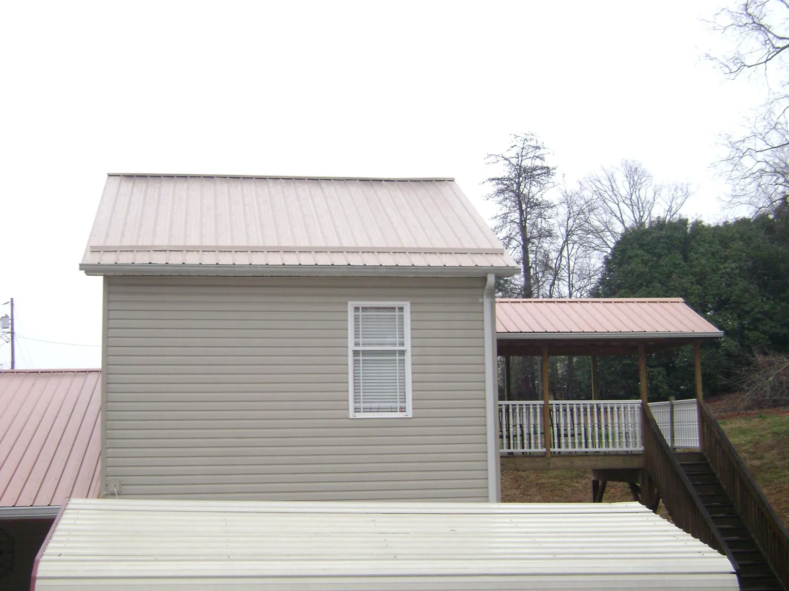 Tan metal roofs on a two story addition and attached porch, from a Roof Replacement job in Tabernash