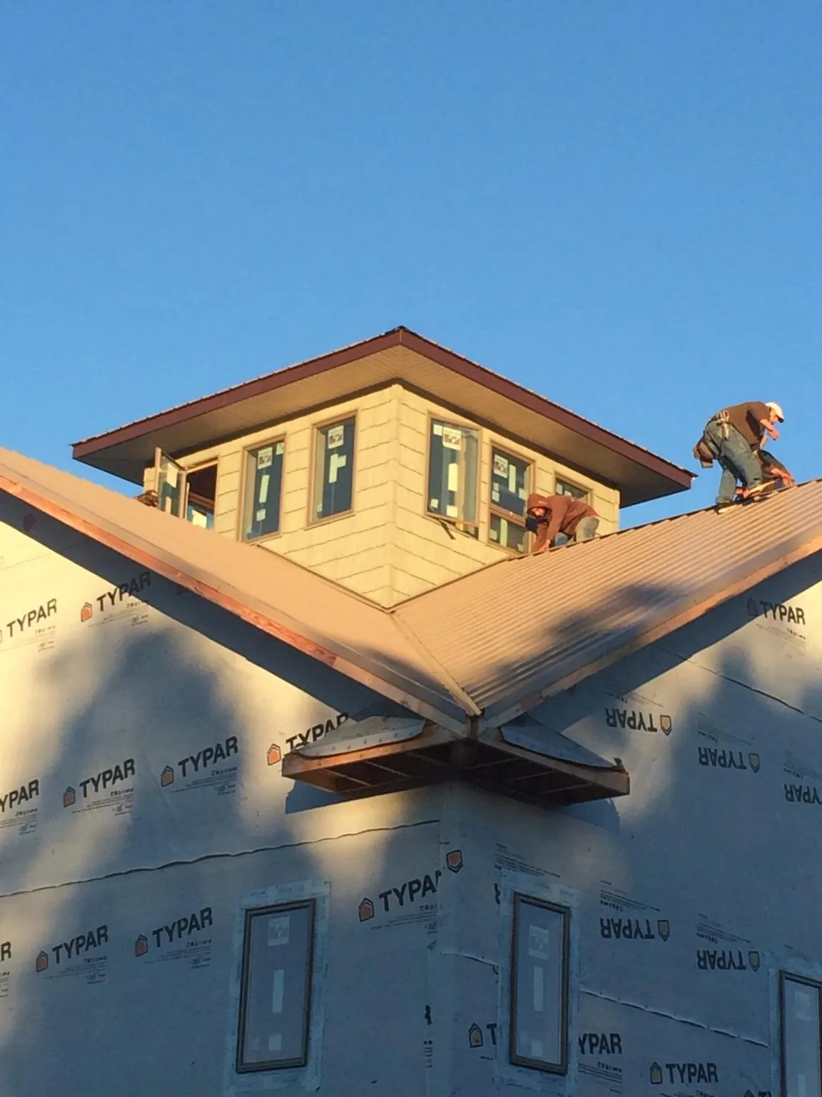 Roofers working around a rooftop cupola on a new metal roof at sunset — Roof Waterproofing in Tabernash by Roofing Brothers